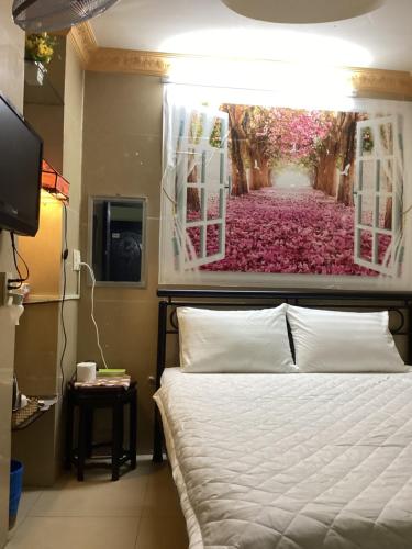 een slaapkamer met een bed met een schilderij aan de muur bij Guest House UTTRANG in Ho Chi Minh-stad