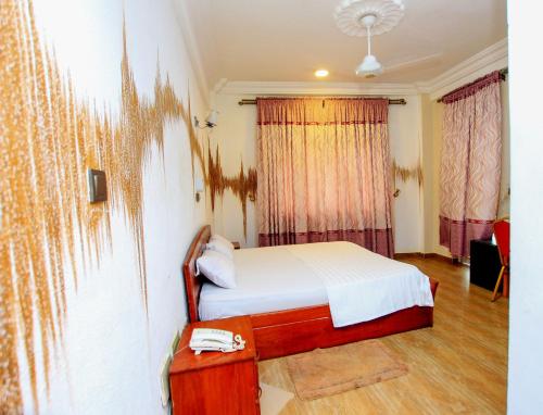 Schlafzimmer mit einem Bett, einem Tisch und Vorhängen in der Unterkunft Benin Metropole Hotel in Parakou