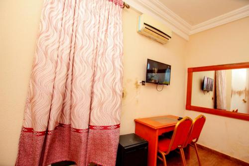 Habitación con escritorio, mesa y cortina en Benin Metropole Hotel, en Parakou