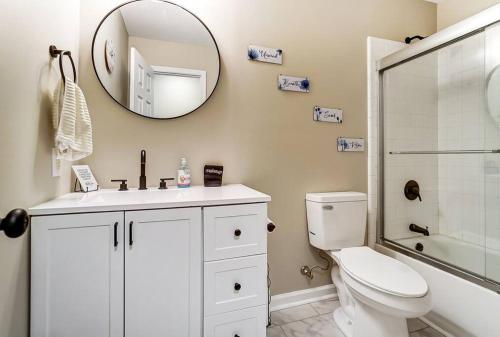 a bathroom with a toilet and a sink and a mirror at Chatlotte Charm Haven with Outdoor TV in Charlotte