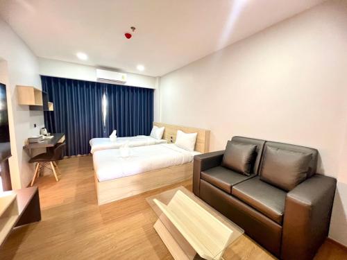 pokój hotelowy z łóżkiem i kanapą w obiekcie JIA HAUS Hotel Apartment w mieście Buri Ram