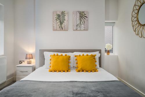 a bedroom with a bed with two yellow pillows at Coppergate Mews Apartment Doncaster 3 in Doncaster