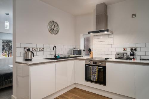 a kitchen with white cabinets and a stove top oven at Coppergate Mews Doncaster Apartment 3 in Doncaster
