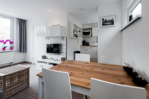 een witte keuken met een houten tafel en witte stoelen bij Vakantiehuisje aan de Kust - nr 33 in Egmond aan Zee