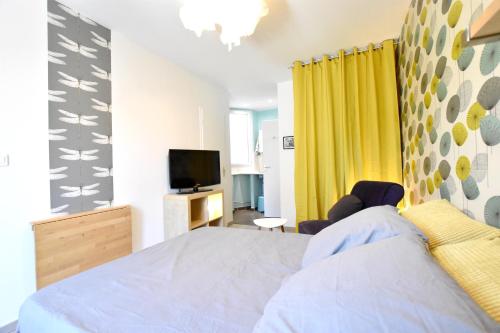 - une chambre avec un lit, une télévision et des rideaux jaunes dans l'établissement Coquet studio centre historique et au calme (4), à Montpellier