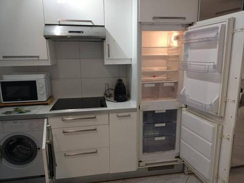 La cuisine est équipée de placards blancs et d'un réfrigérateur ouvert. dans l'établissement joli studio design balcon sud et parking gratuit, à La Garde