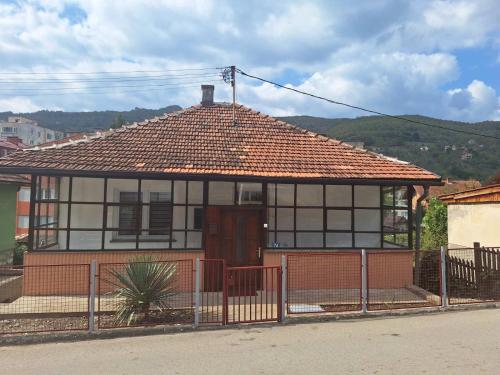 une maison avec un toit en carrelage et une clôture dans l'établissement Apartman Vuković, à Foča