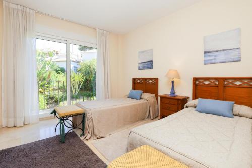 een slaapkamer met 2 bedden en een raam bij Los Monteros Palm Beach - sea & pool view in Marbella