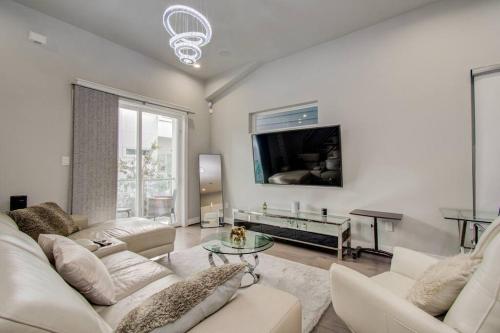 a living room with white furniture and a flat screen tv at Luxurious Med Cntr/NRG Townhome in Houston