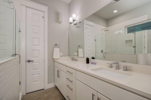 a white bathroom with two sinks and a mirror at Luxurious Med Cntr/NRG Townhome in Houston