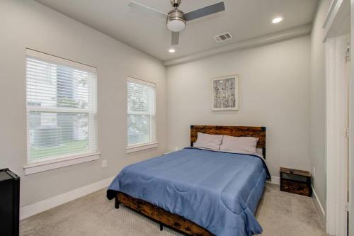 a bedroom with a blue bed and two windows at Luxurious Med Cntr/NRG Townhome in Houston