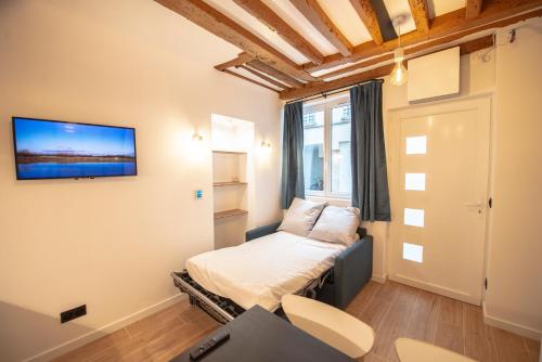 mały pokój z łóżkiem i telewizorem na ścianie w obiekcie Appartement cosy Montorgueil (Bonne Nouvelle) w Paryżu