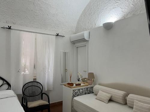 Villa Manni في بروسيدا: غرفة بيضاء بسرير واريكة وكرسي