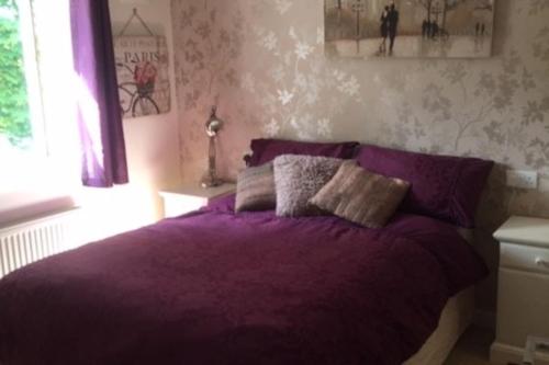 um quarto com uma cama com lençóis roxos e uma janela em Close to Jurassic Coast 3 Bed modern house em Wool