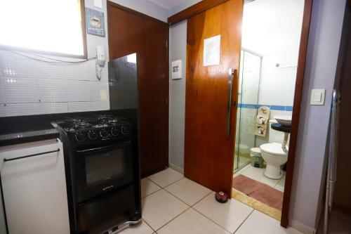 eine Küche mit einem Herd und ein Badezimmer mit einem WC in der Unterkunft Winterville Gravatá Flat 425 - Próximo das piscinas in Gravatá