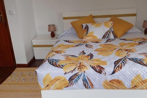 a bed with a floral comforter and pillows on it at Sol e Mar by the airport in Santa Cruz