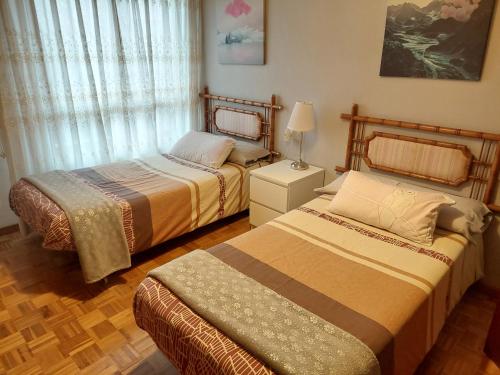 een slaapkamer met 2 bedden en een lamp bij apartamento central in Ribadesella