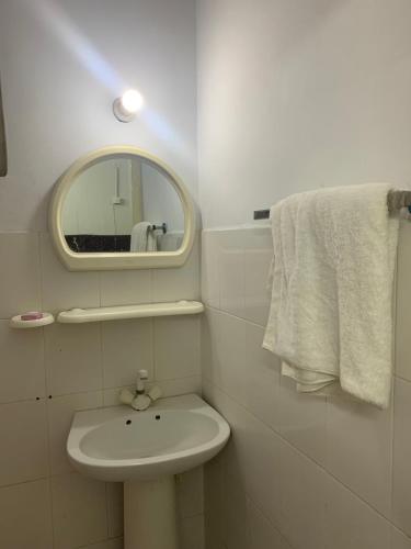 uma casa de banho branca com um lavatório e um espelho em Eden Plus Executive Hotel em Lahore