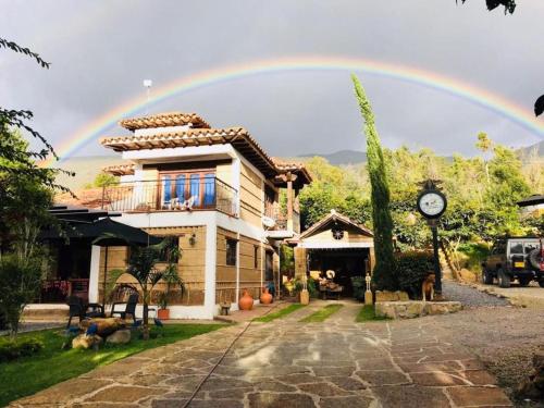 a rainbow in the sky above a house at Hotel Casa Cantabria Campestre in Villa de Leyva