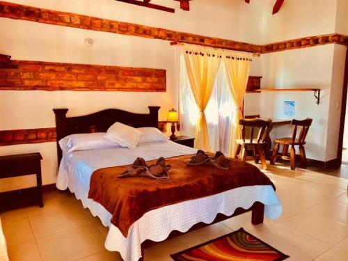 a bedroom with a large bed with shoes on it at Hotel Casa Cantabria Campestre in Villa de Leyva