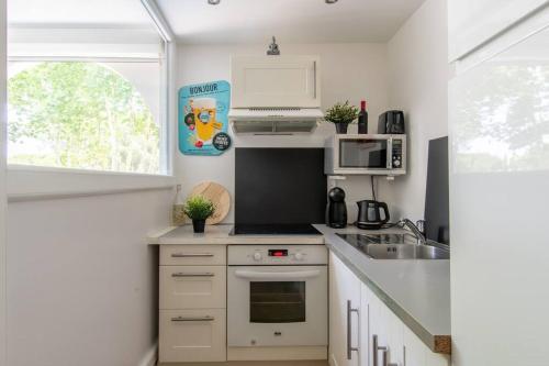 une petite cuisine avec une cuisinière et un micro-ondes dans l'établissement Le Corail * Charmant T2 * Clim Réversible * Ponant * Rénové * Lumineux, à La Grande Motte