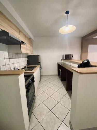 a large kitchen with white tile flooring and a kitchen with a stove at Appartement au centre-ville avec cour in Langres