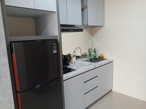 a kitchen with a black refrigerator and white cabinets at MESA Thamrin City Apartments at Nagoya with Netflix & Pick Up Service in Nagoya