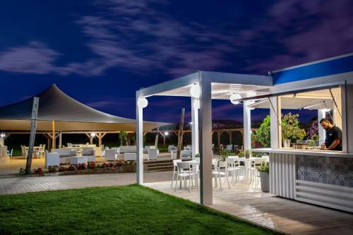 a man sitting at a bar under a pavilion at night at Parco Della Gallinara in Lido dei Pini