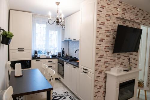 a kitchen with white cabinets and a tv on a brick wall at Urban Oasis in Piatra Neamţ