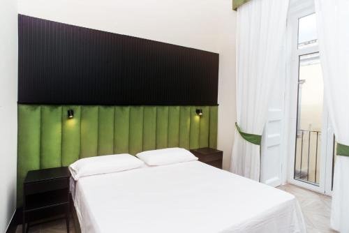 ein Schlafzimmer mit einem weißen Bett und einer grünen Wand in der Unterkunft FiDa Rooms in Neapel