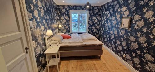 a small bedroom with a bed with blue and white wallpaper at Rymlig dalastuga i Siljansnäs 4-6 bäddar in Siljansnäs