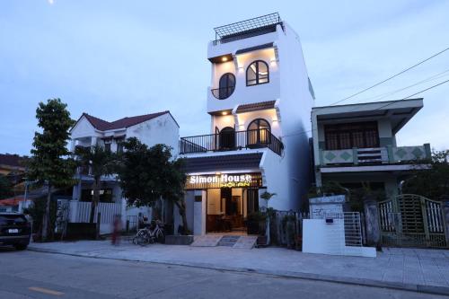 a tall white building with lights on it at Simon House Hoi An in Hoi An