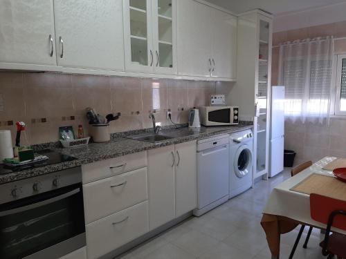 a kitchen with white cabinets and a sink and a dishwasher at Mary Apartments in Almada