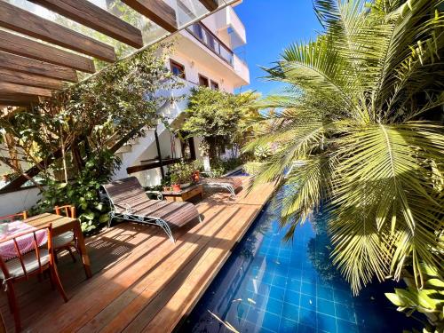 - une piscine avec une terrasse en bois et des palmiers dans l'établissement Hotel Vila Nova do Príncipe, à Caetité