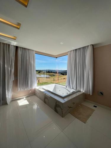 a large bathroom with a tub in front of a window at Hope Valley Adventure Resort in Guarapuava