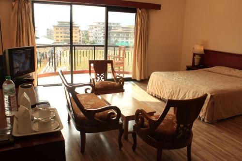 um quarto com uma cama, 2 cadeiras e uma mesa em The Orchid Hotel em Phuntsholing