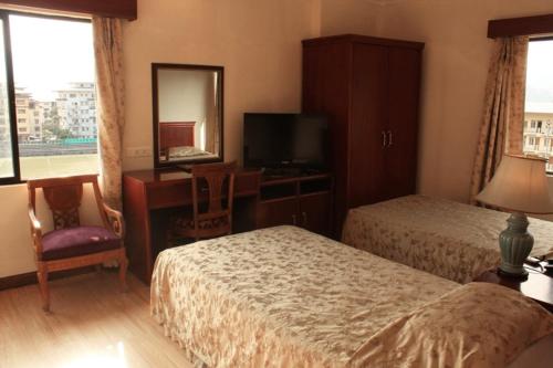 um quarto de hotel com duas camas, uma secretária e um espelho em The Orchid Hotel em Phuntsholing