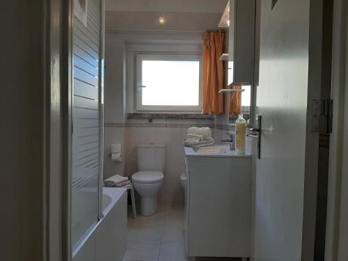 a bathroom with a toilet and a sink and a window at Mary Apartments in Almada
