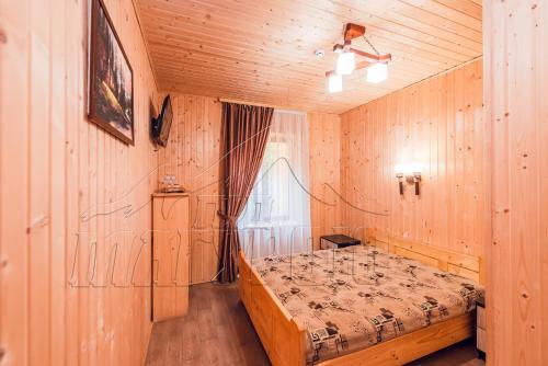 a bedroom with a bed in a room with wooden walls at ПІД МАГУРОЮ in Pilipets