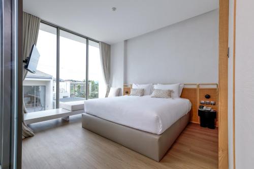 a bedroom with a white bed and a large window at Lavanda Hotel Chiang Rai in Ban Long O