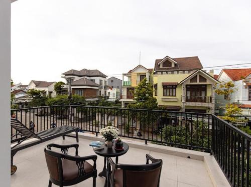 a balcony with a table and chairs and houses at Simon House Hoi An in Hoi An