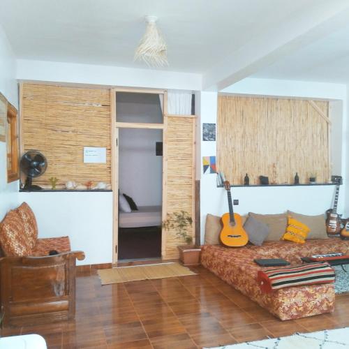 - un salon avec un canapé et une guitare dans l'établissement Idriss's hostel, à Taghazout