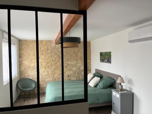 SoussansにあるGîte avec spa privatif à 500m de MARGAUXのベッドルーム1室(緑のベッド1台、ガラスの壁付)