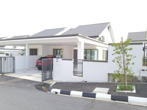 a white house with a gate and a car at One Sweet Homestay Kulim Hi-Tech utk Msliim shj in Kulim