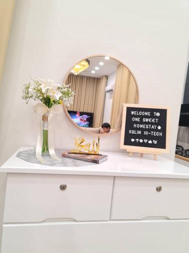 a dresser with a vase of flowers and a mirror at One Sweet Homestay Kulim Hi-Tech utk Msliim shj in Kulim
