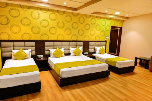 a bedroom with two beds and a yellow wall at Trimrooms Buddha Varanasi in Varanasi