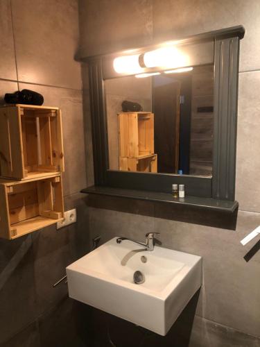 een badkamer met een witte wastafel en een spiegel bij B&B de Garaazje in Workum