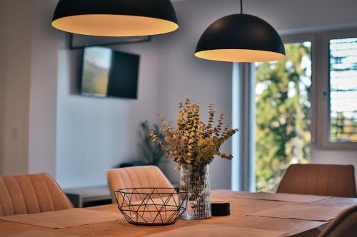 a dining room table with a vase of flowers and two lights at Apartmány Lipno Přední Výtoň in Přední Výtoň