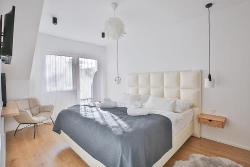 a white bedroom with a large bed and a chair at Apartmány Lipno Přední Výtoň in Přední Výtoň
