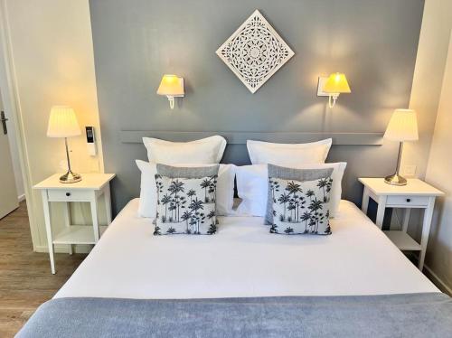 1 dormitorio con 1 cama blanca con almohadas y 2 mesas en Hôtel Les Vieilles Tours Rocamadour en Rocamadour